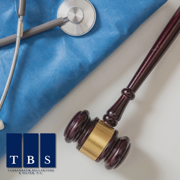 A stethoscope and a judge’s gavel rest on a blue medical cloth, with the TBS law firm logo in the lower left corner—symbolizing the dedication of Personal Injury Lawyers in Garden City.